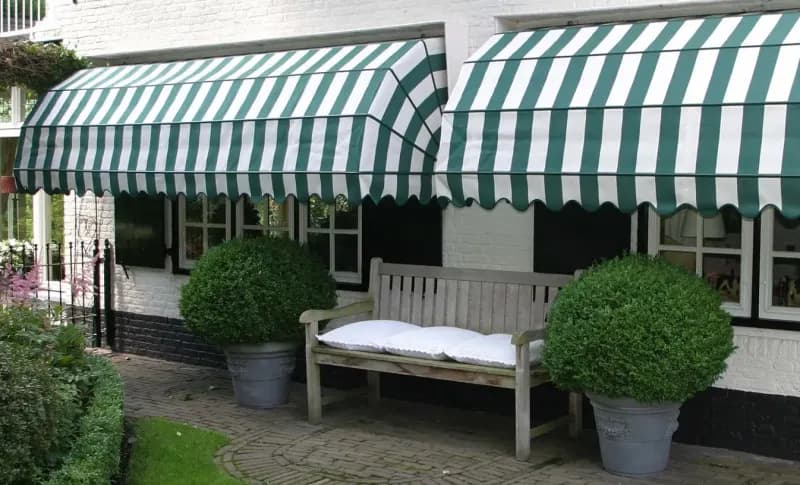 Groen-witte markies als traditionele zonwering aan een gevel